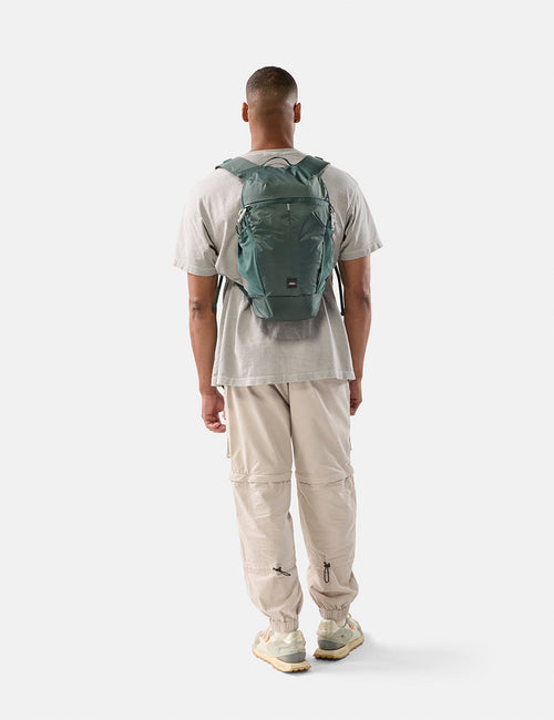 Person wearing a green backpack on a white background