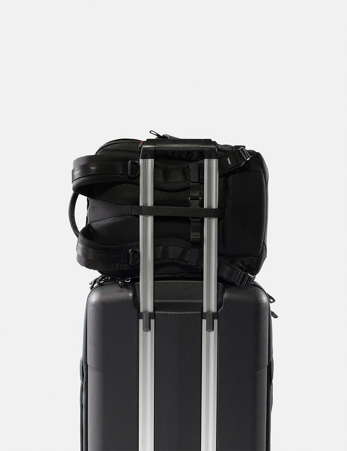 Black backpack and suitcase stacked on a white background