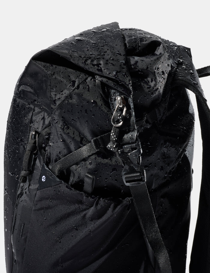 Black backpack with water droplets on a white background