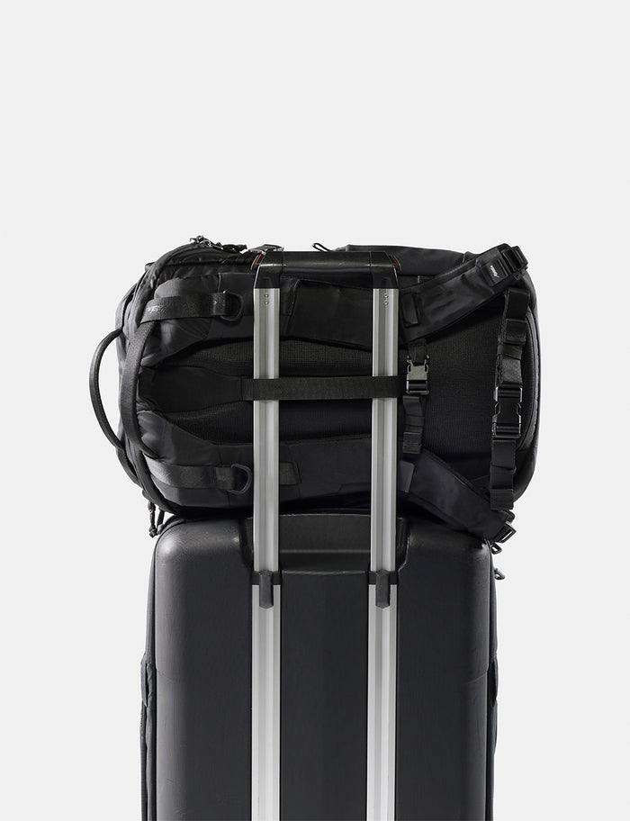 Black backpack attached to a black suitcase on a white background