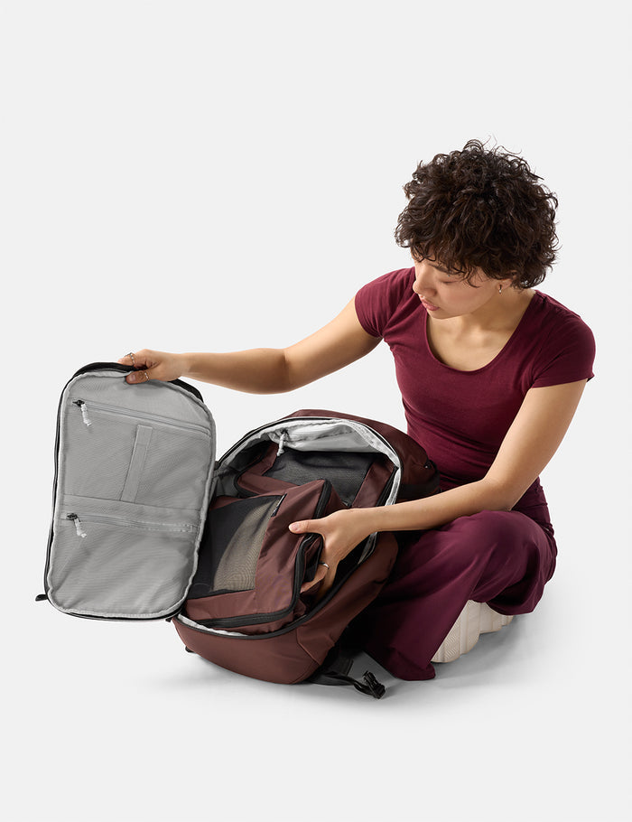 Person opening a large backpack on a white background