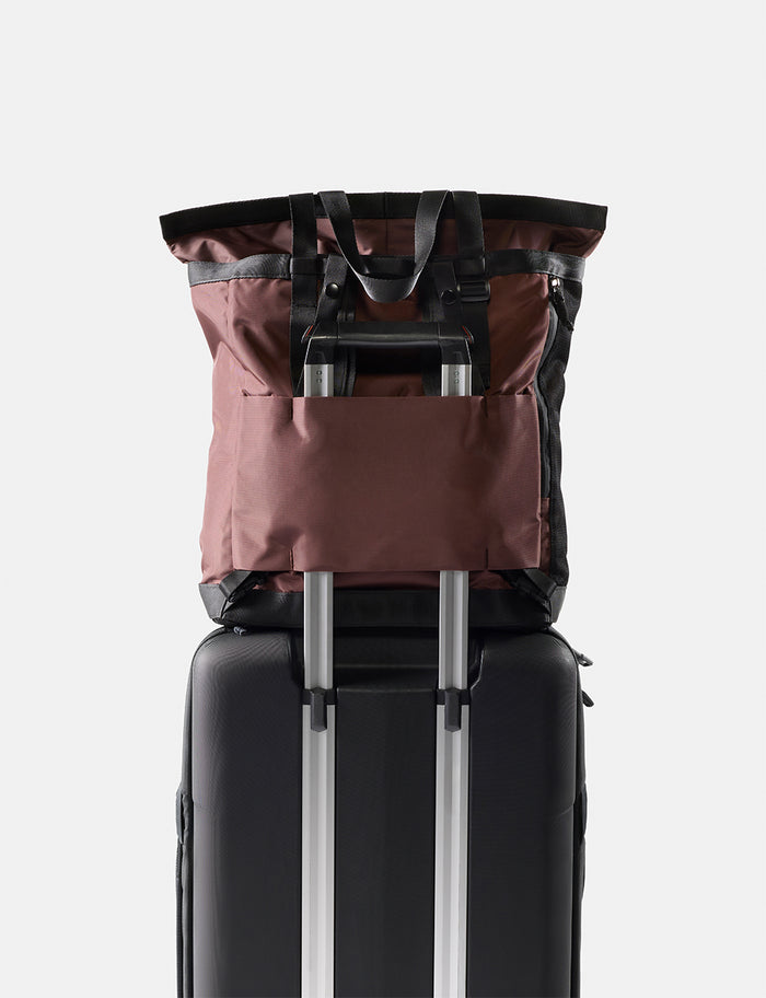 Black suitcase with a garnet backpack on top against a white background