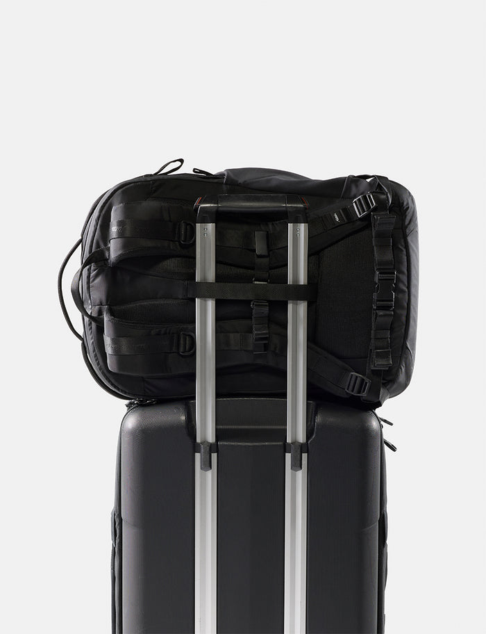 Black backpack on top of a black suitcase with a white background