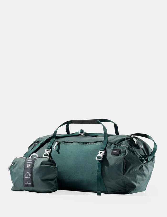 Green travel bag with smaller pouch on a light gray background