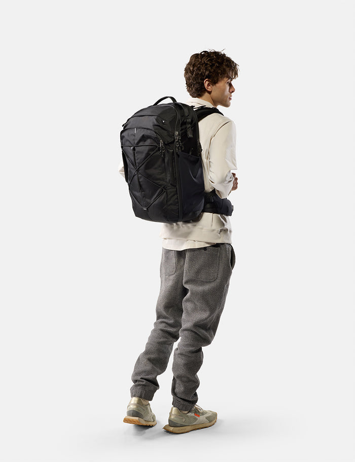 Person wearing a black backpack on a white background