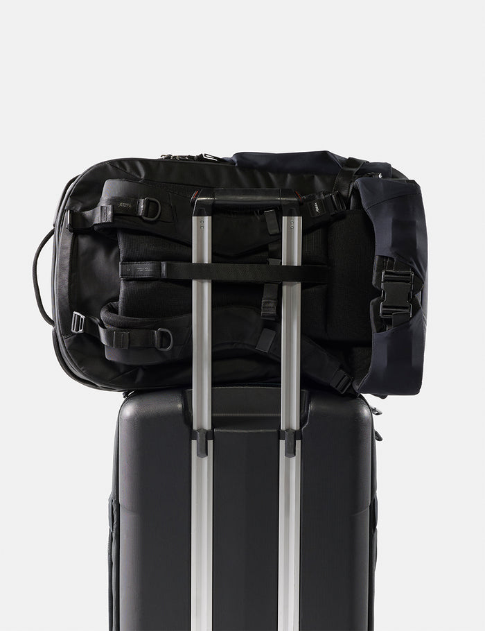 Black backpack on top of a suitcase with a white background