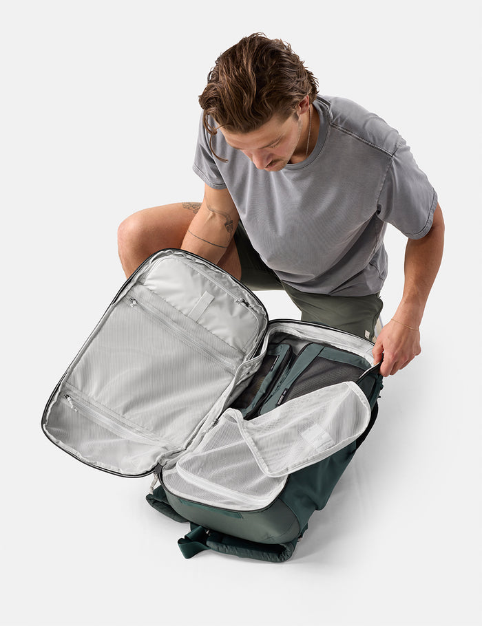 Person opening a gray backpack on a white background
