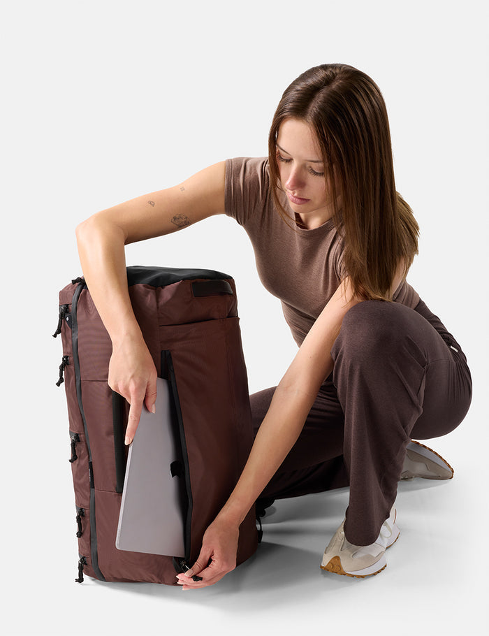 Woman organizing a large Garnet backpack on a white background