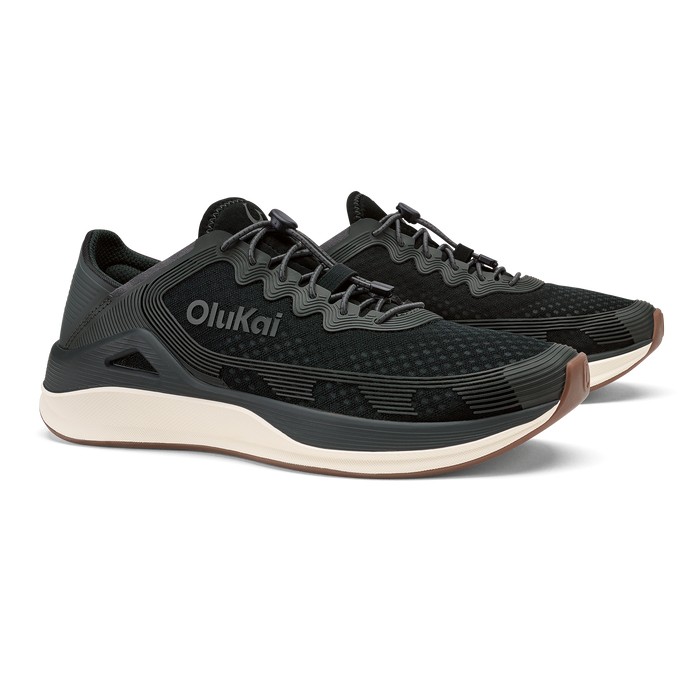 Black OluKai ʻAhi running shoe with cream-colored sole and charcoal grey accents, shown from the side.