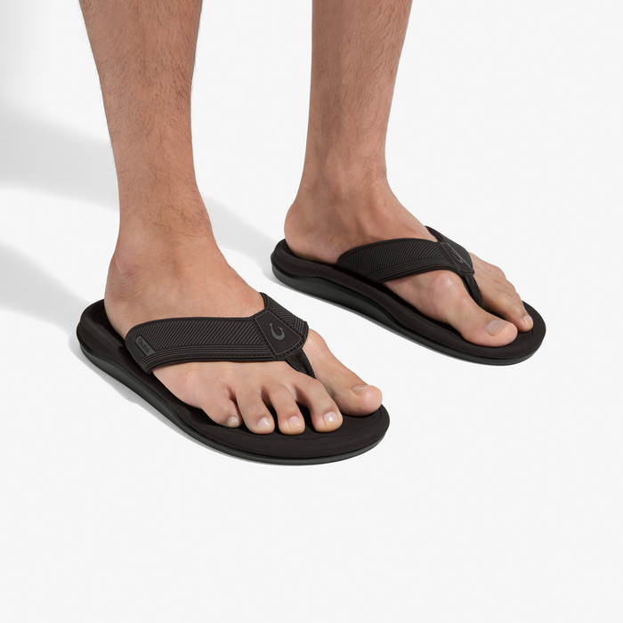 Black thong flip-flops with textured toe straps and cushioned soles worn on feet.