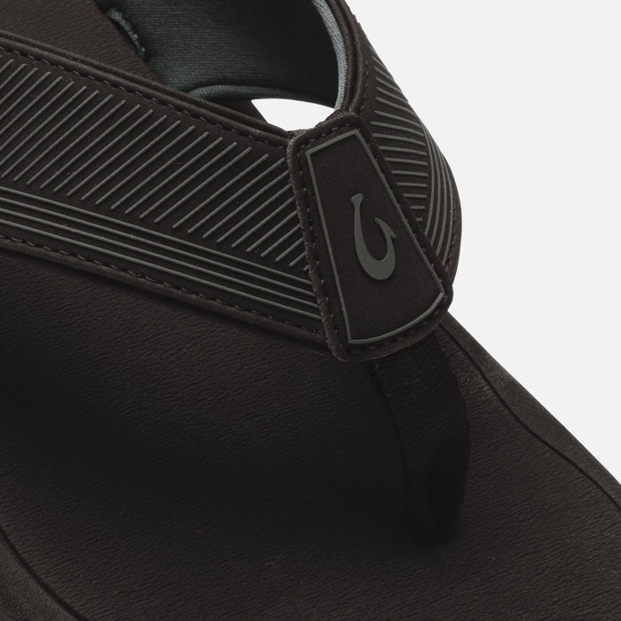Black slide sandal with textured ribbed straps and logo patch detail on the upper.