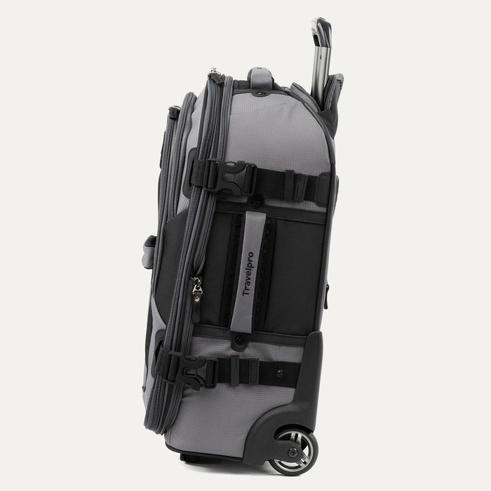 side view of the gray black bold by travelpro carry-on expandable rollaboard suitcase standing vertically, showing its durable gray fabric accent panels, padded side carry handle, exterior compression straps with buckles, a high-performance corner-mounted wheel, and the extended telescoping handle.
