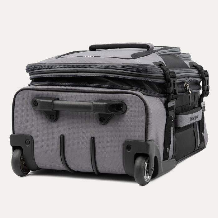 low-angle rear view of the gray black bold by travelpro carry-on expandable rollaboard suitcase resting horizontally, showcasing its two high-performance ball-bearing wheels, heavy-duty protective skid guards, and the molded housing around the retracted telescoping handle.