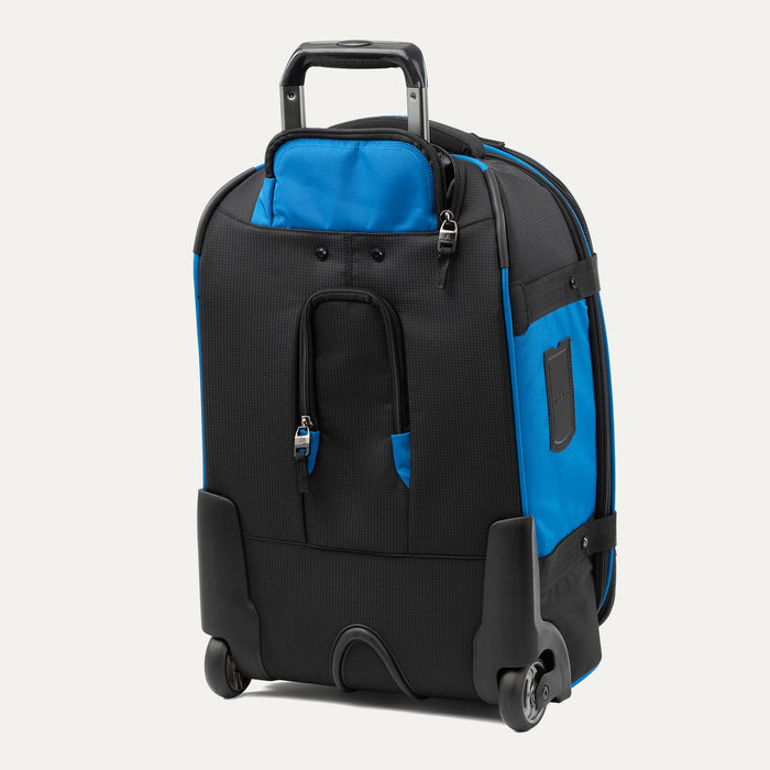 rear three-quarter view of the blue black bold by travelpro carry-on expandable rollaboard suitcase standing vertically, showing its protective skid guards, molded corner guards, reinforced wheel housings, two high-performance ball-bearing wheels, and extended telescoping handle.