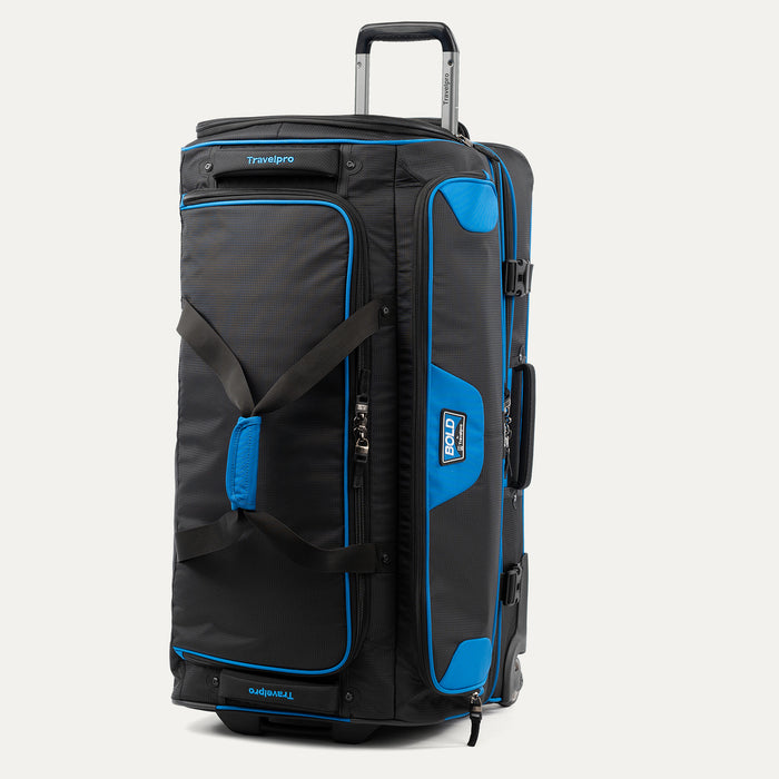 upright front three-quarter view of the blue black bold by travelpro large check-in drop-bottom rolling duffel bag standing vertically, showcasing its rugged polyester exterior, bright blue accents, dual carrying handles, and extended telescoping aircraft-grade handle.