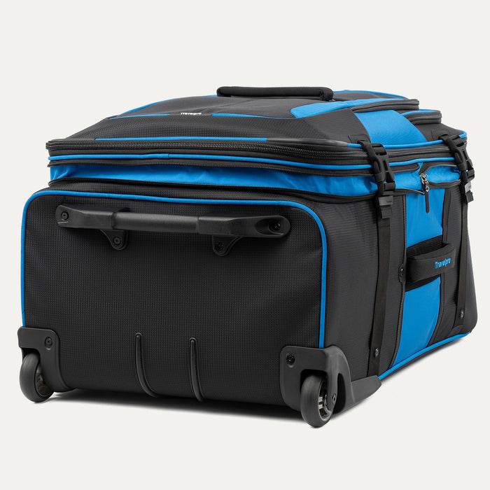 low-angle rear view of the blue black bold by travelpro large check-in expandable rollaboard suitcase resting horizontally, showcasing its two high-performance ball-bearing wheels, heavy-duty skid guards, and the molded housing around the retracted telescoping handle.