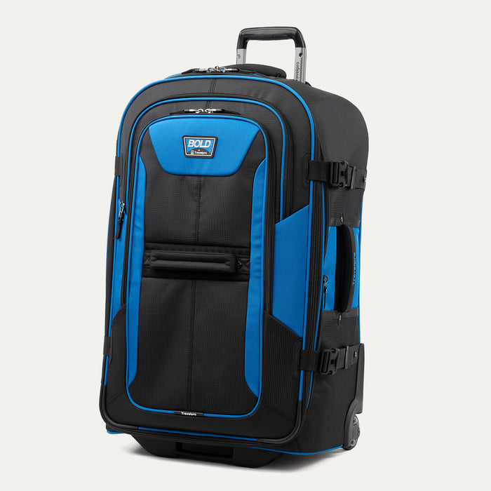 upright front three-quarter view of the blue black bold by travelpro large check-in expandable rollaboard suitcase standing vertically, showcasing its rugged black and blue polyester exterior, dual front zippered pockets, and extended telescoping aircraft-grade handle.