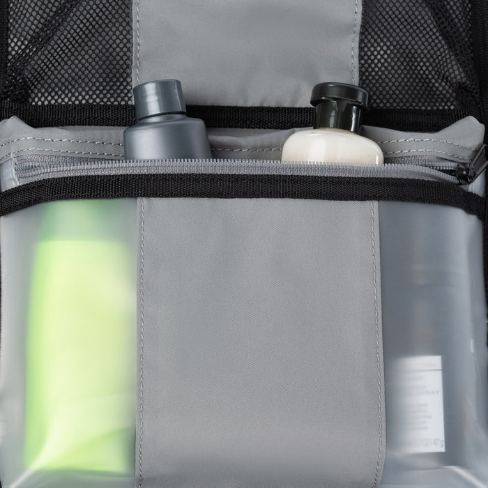 Close-up interior view of the Crew Classic Carry-On Spinner, highlighting the water-resistant, transparent storage pockets filled with travel-sized bottles and toiletries against a clean off-white background.
