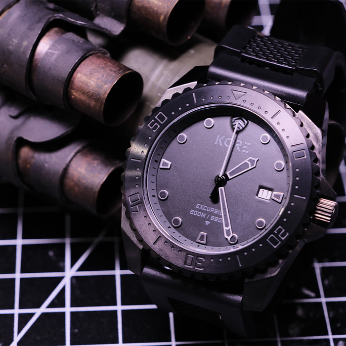 Closeup of  a kore essentials excursion tactical field watch on a checkered background with spent shell casings