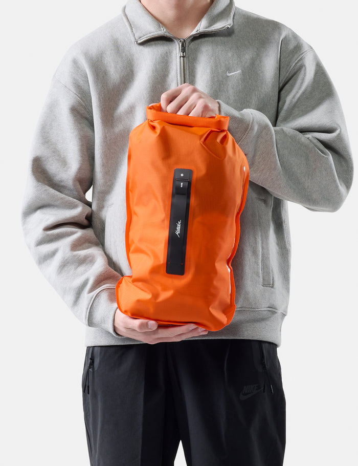Person holding an orange bag against a white background