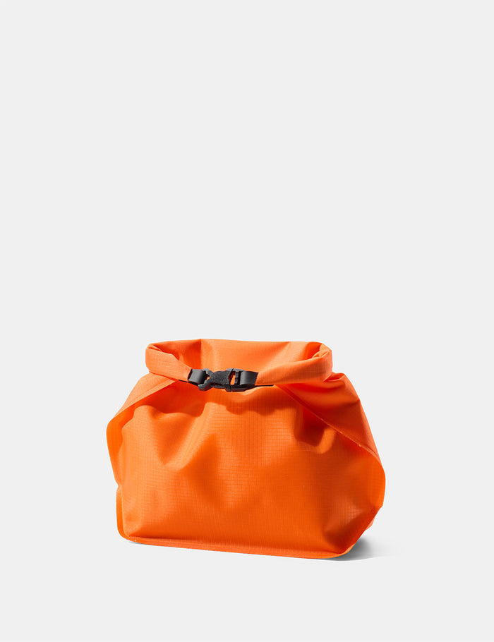 Orange toiletry bag with a black buckle on a light gray background