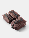Three garnet gear cubes with zippers on a light gray background