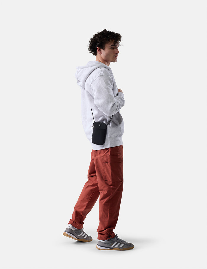 man on white background wearing travel wallet cross body