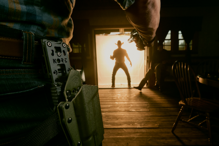 Two men in a stand off with one wearing a black kore essentials holster mount