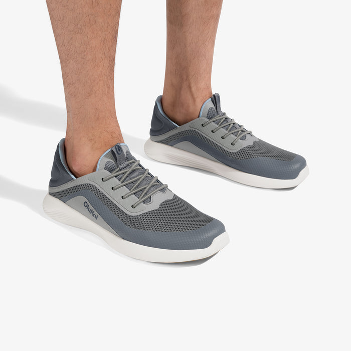 Charcoal and gray lace-up sneakers with white soles worn on feet.