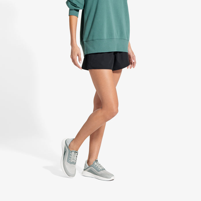 Person wearing teal sweatshirt and black shorts with gray and white sneakers.