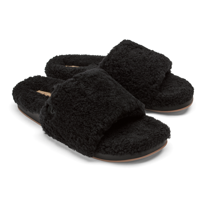 Pair of black fuzzy slippers with tan leather soles and cushioned footbeds.