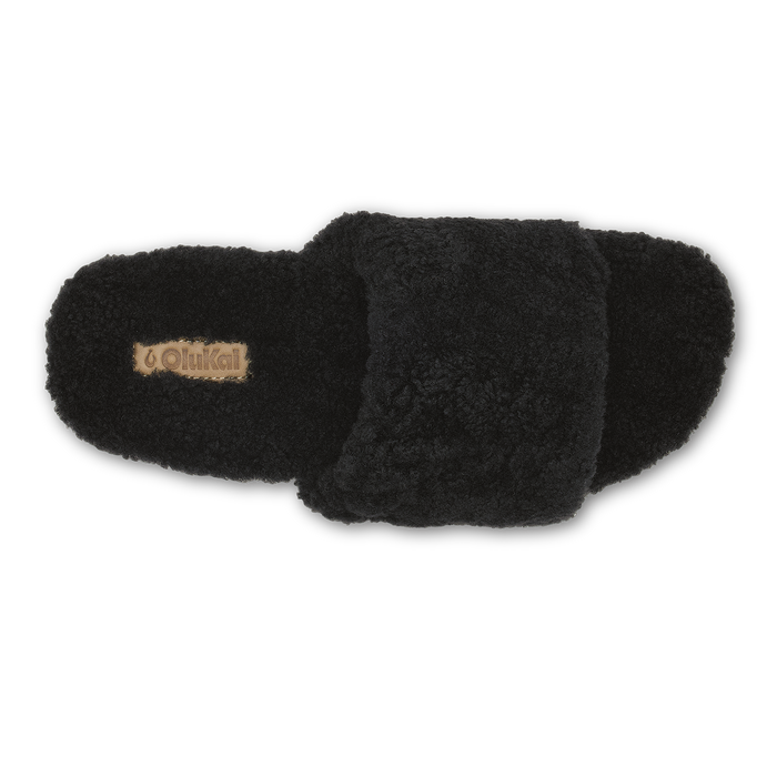 Black fuzzy slippers with tan brand label on left slipper, shown from above.