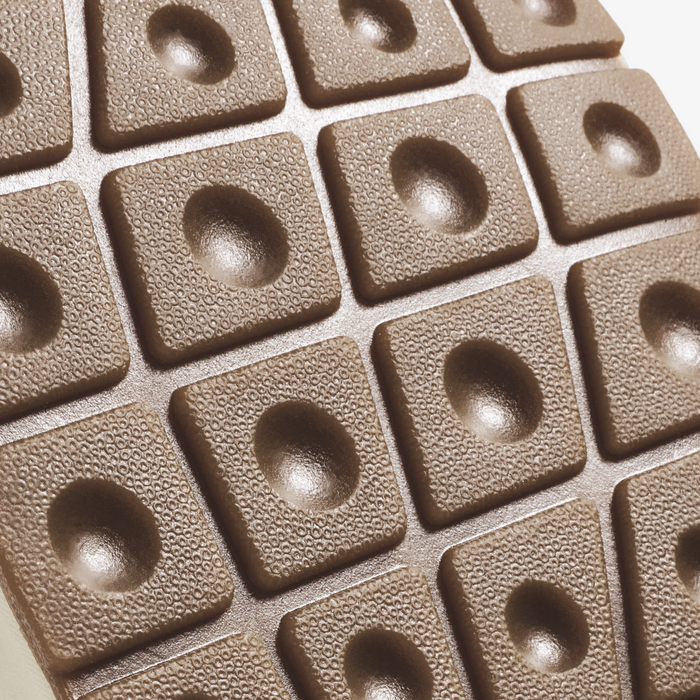 Beige textured tiles with circular recessed centers arranged in a grid pattern.