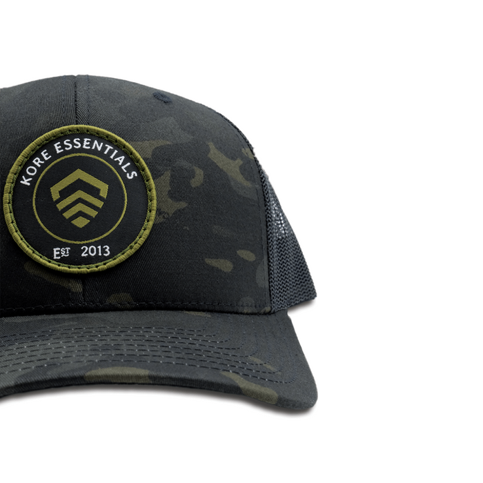 Side View of Multicam® Black Kore Essentials Trucker Cap with Kore Logo Embroidered on Front