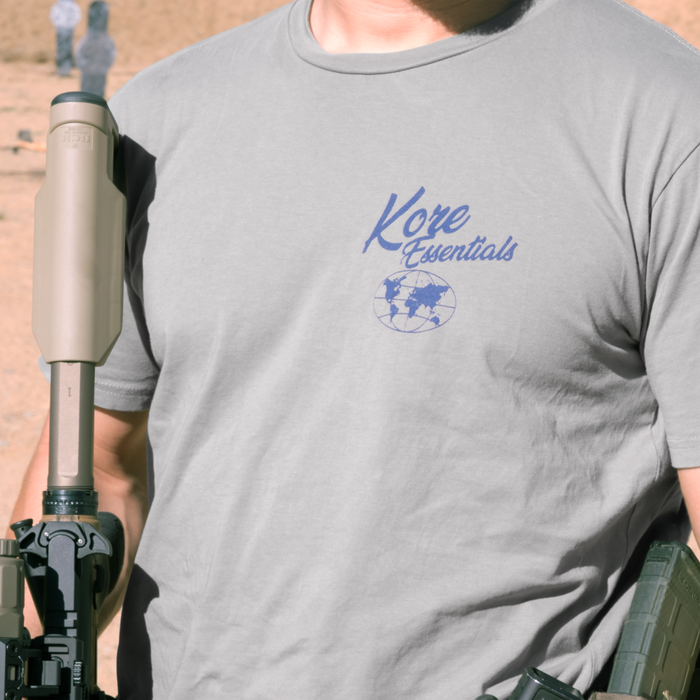 Person wearing a gray t-shirt with 'Kore Essentials' logo holding a rifle.