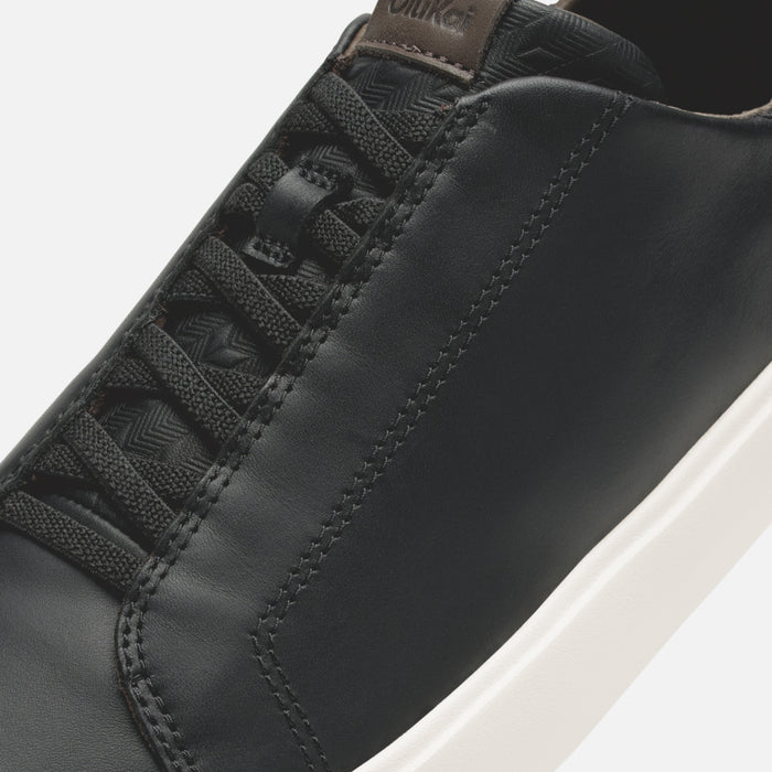 Black leather sneaker with geometric patterned laces, brown heel tab, and white sole.
