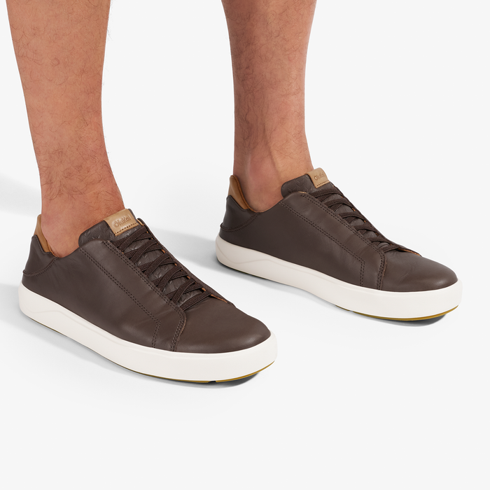 Dark brown leather sneakers with tan heel collar and white crepe sole, worn by model.