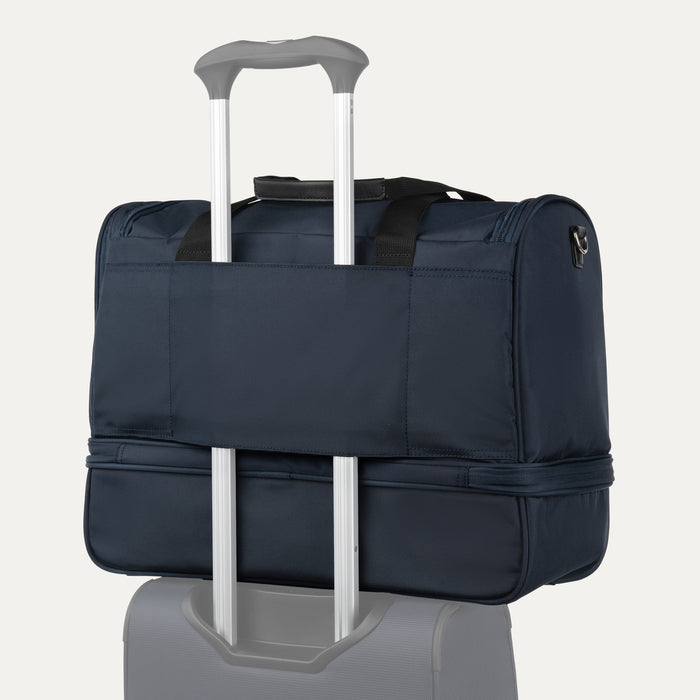 rear view of midnight blue travelpro maxlite 5 drop bottom weekender showing the stacking strap secured over the telescoping handle of a rolling suitcase.