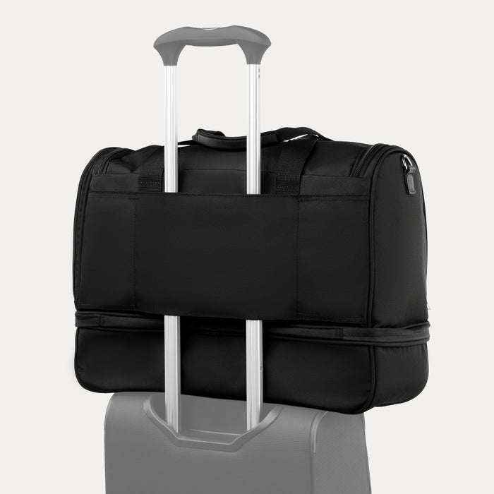 rear view of the black travelpro maxlite 5 drop bottom weekender showing the integrated rear strap slipped over the telescoping handle of a suitcase for secure stacking.