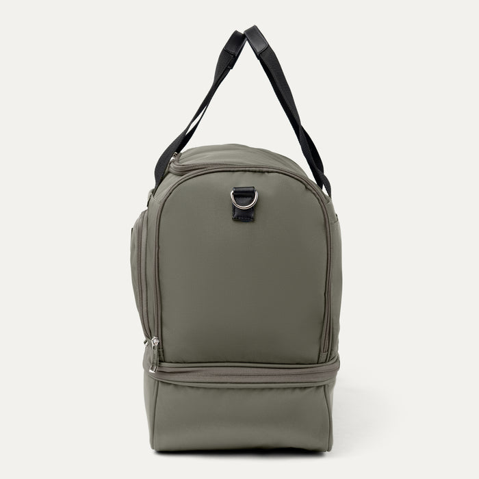 side profile view of the slate green travelpro maxlite 5 drop bottom weekender bag showing the zippered lower compartment and the black webbing carry straps.