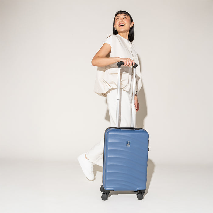 Person walking with the Travelpro Maxlite Air Carry-On Hardside Spinner in Ensign Blue, highlighting lightweight maneuverability.