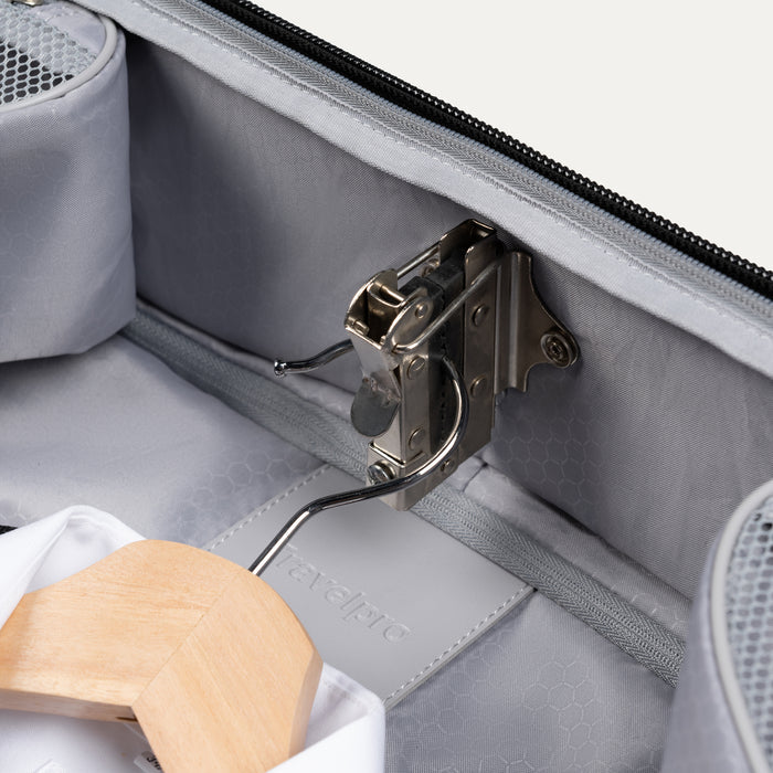 close up of metal interior hanger clamp in black travelpro maxlite checked rolling garment bag holding a wooden suit hanger.