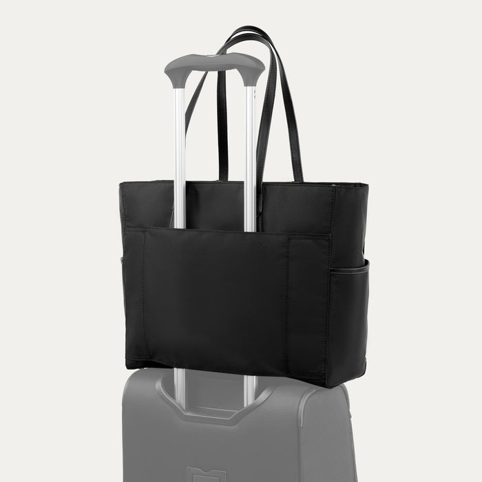 rear view of black travelpro maxlite women's tote showing the integrated stacking strap slipped over the telescoping handle of a suitcase for hands-free mobility.