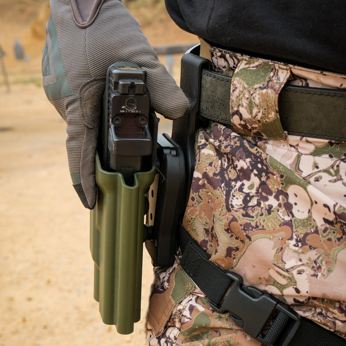 A person wearing camouflage stands wearing a Kore Essentials 1.5" Mount Mini and a Kore Locking System
