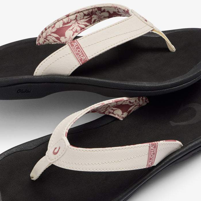 White and onyx flip-flops with floral patterned straps and cushioned soles shown from top and side angles.