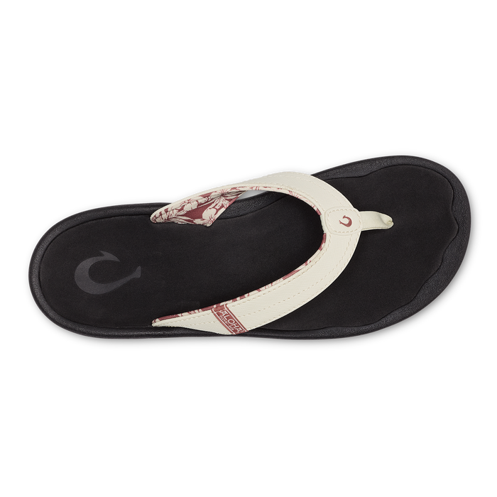 White and black flip-flop sandal with floral patterned strap detail, viewed from above.