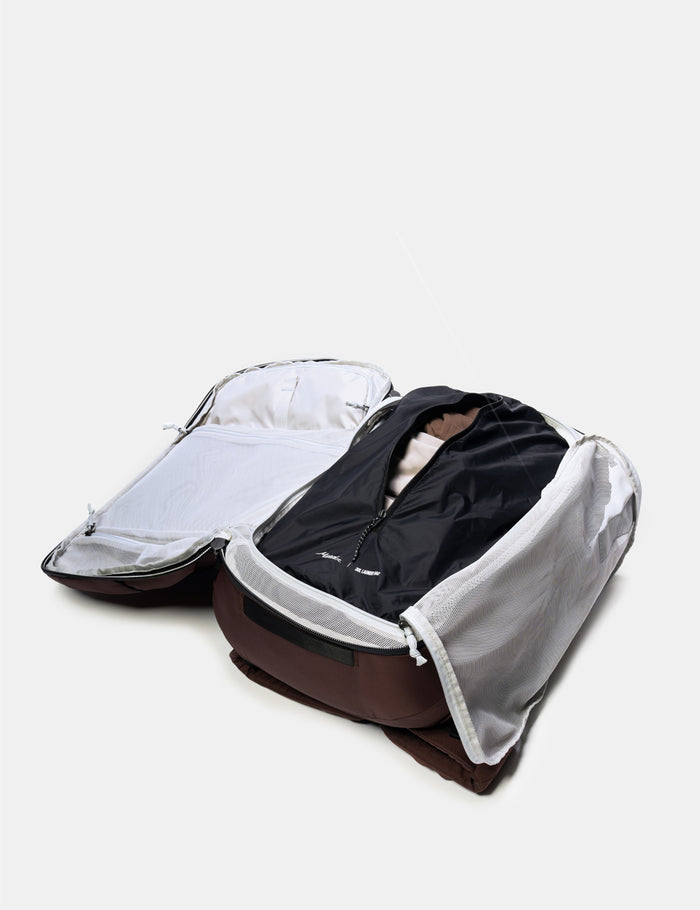 Open backpack with dirty clothes on a light gray background