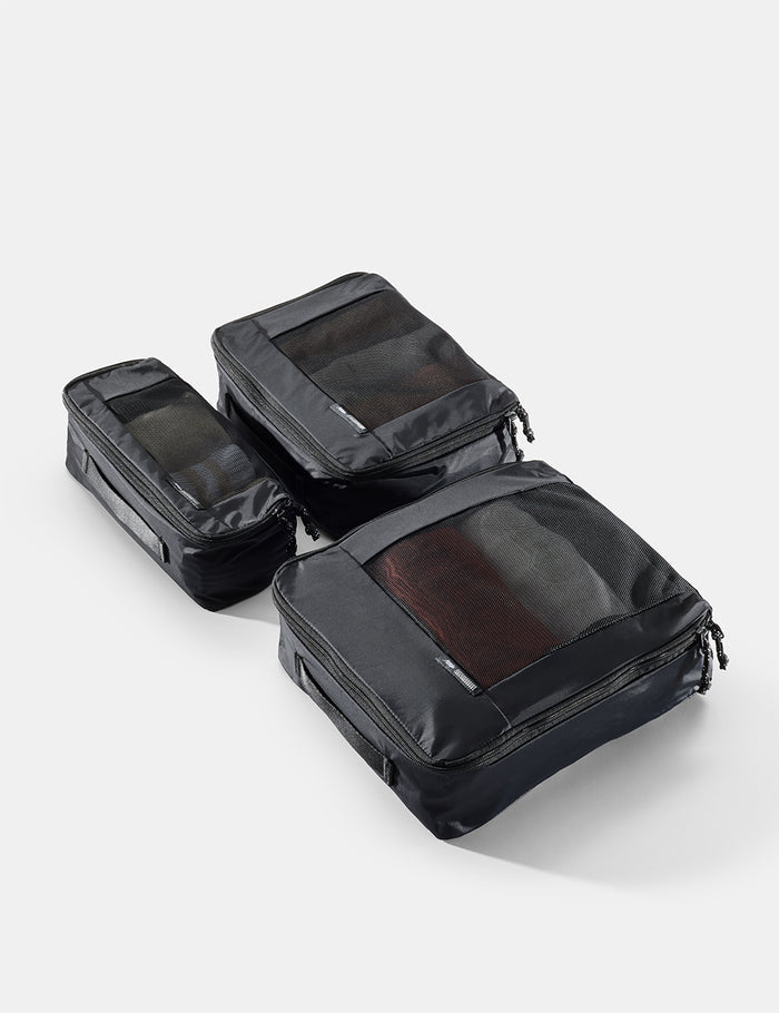 Set of black travel packing cubes on a light gray background