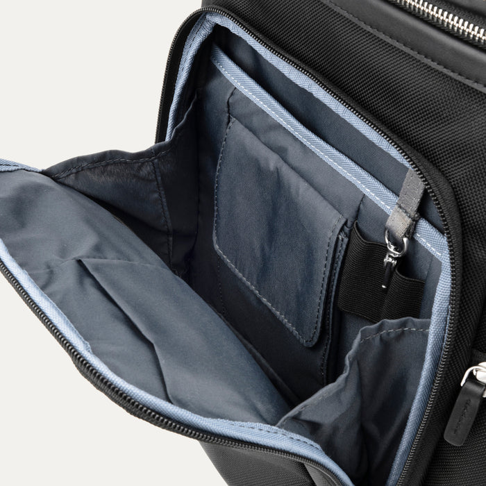 interior view of the front organizational compartment of the black travelpro platinum elite business laptop backpack 27l, showing built-in pockets for pens, a key tether, and a small zippered security pocket.