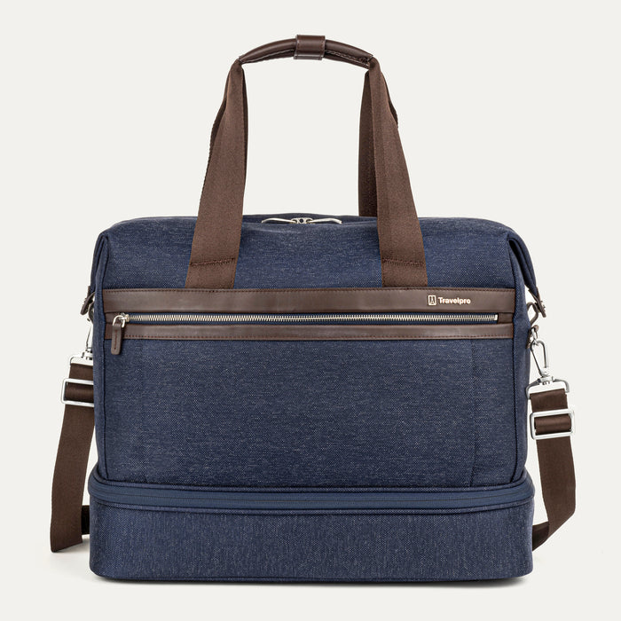 front view of the true navy travelpro platinum elite drop-bottom weekender bag, featuring its signature two-compartment design with premium brown leather trim, chrome zippers, and a removable shoulder strap.